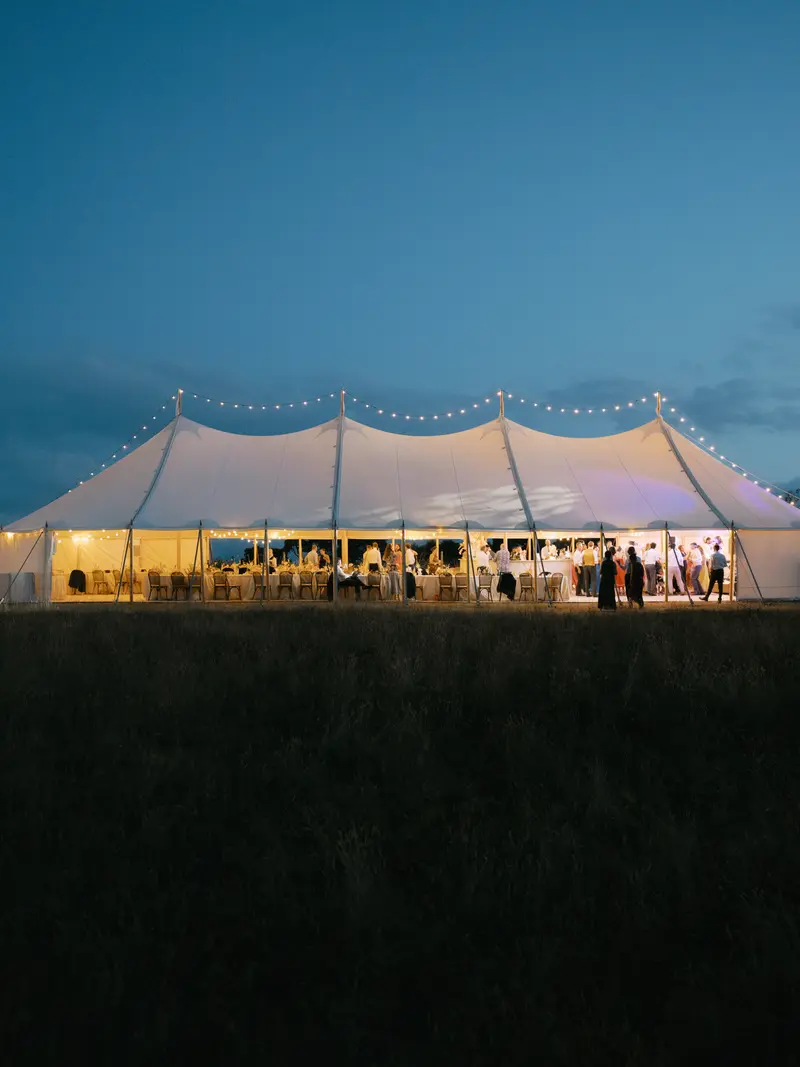 A wedding marquee glowing in a garden at dusk
