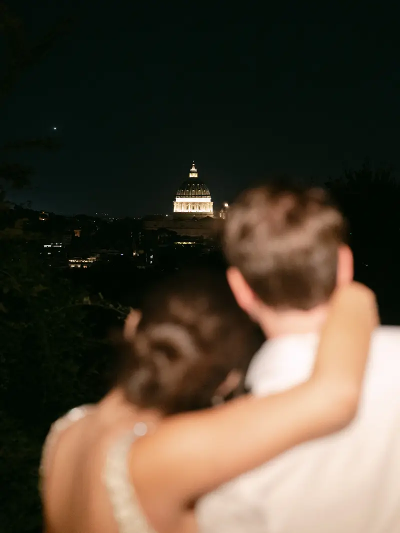 A couple at night facing a dome in Rome